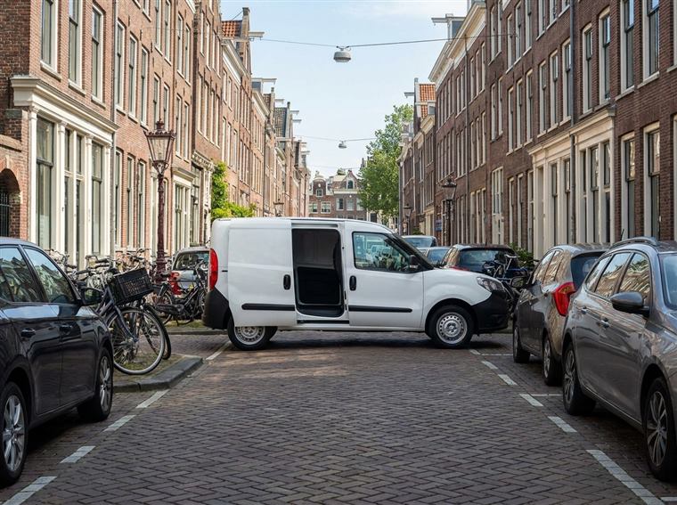 Compacte witte bestelbus in een smalle Nederlandse straat